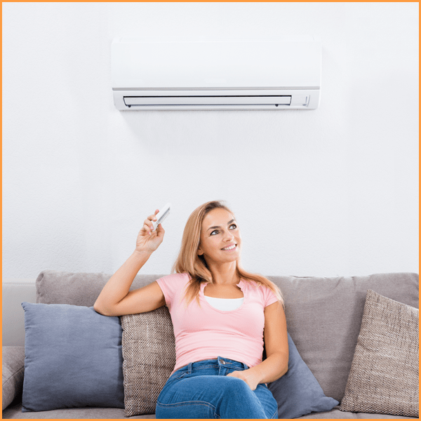 Woman Sitting On Couch Operating Air Conditioner
