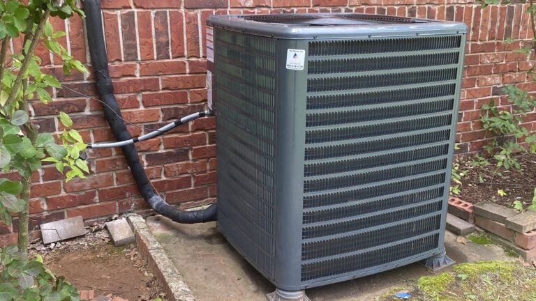 AC not cooling? A central air conditioner condenser installed by Monarch Heating & Air beside a brick home in the Oklahoma City metro