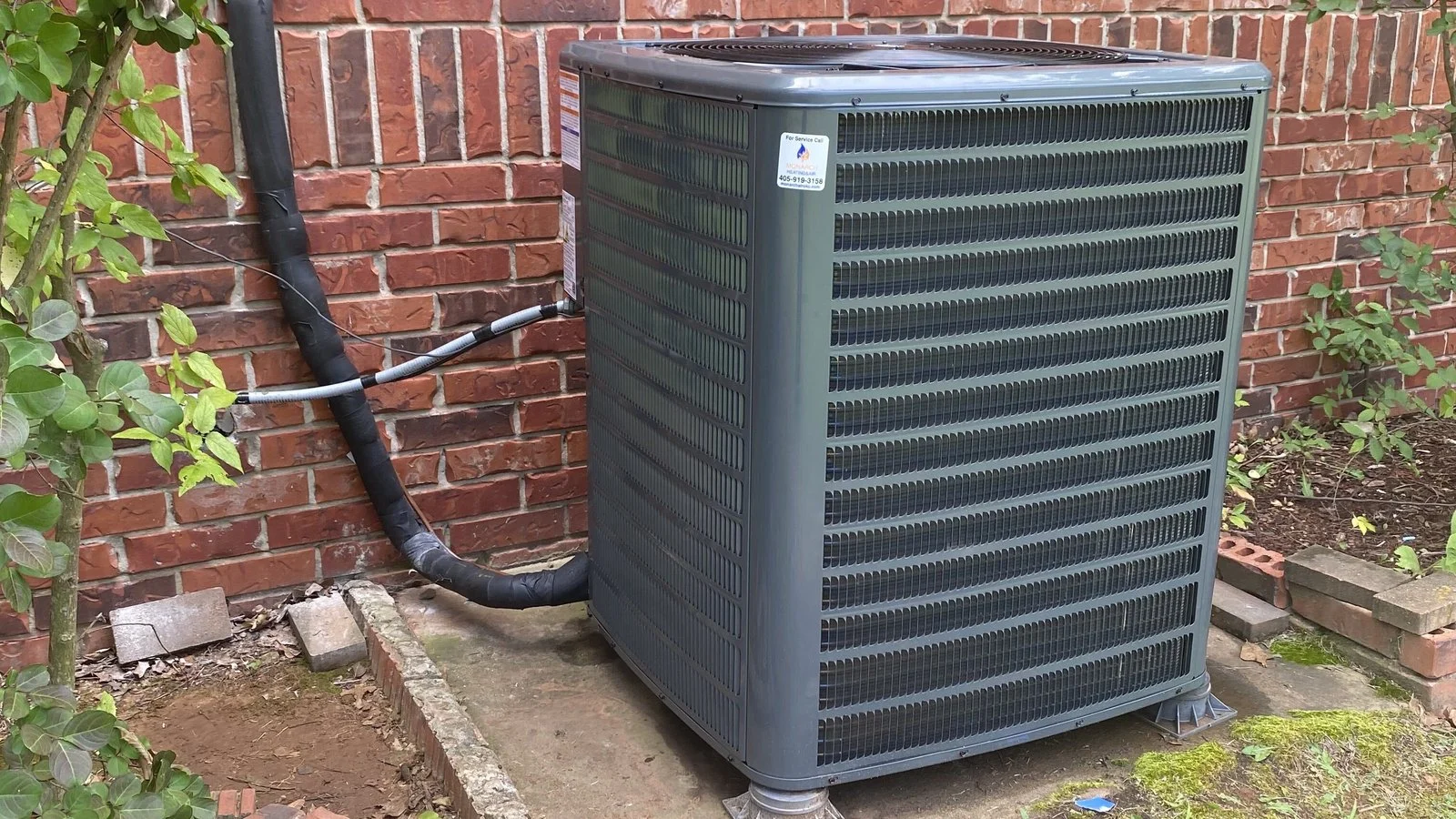 AC not cooling? A central air conditioner condenser installed by Monarch Heating & Air beside a brick home in the Oklahoma City metro